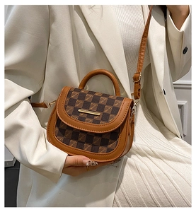 Detail of checkered mini crossbody bag with golden metal trim and leather handle