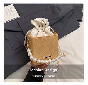 Detail of cubic woven bucket bag featuring large pearl handle and gold chain strap