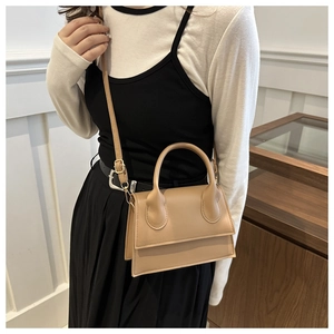 Model wearing a chic apricot square handbag with gold hardware and adjustable strap