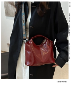 Close-up of deep red glossy PU leather bag with colorful geometric woven shoulder strap