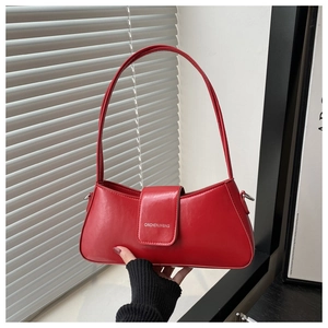 Close-up of red leather hobo bag featuring magnetic flap and brand logo lettering