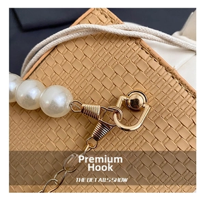 Close-up of beige woven leather texture with white pearl strap and gold metal hooks