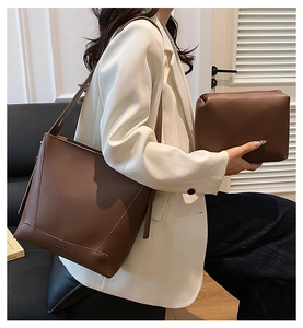 Detail view of deep brown leather bucket bag set with matching pouch on a model