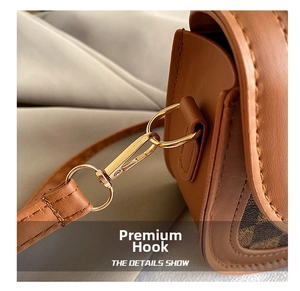 Detail of premium gold metal hook and textured leather strap on a saddle bag