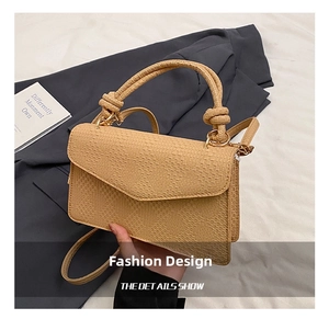 Close-up of tan woven texture handbag with knotted handle and gold metal clasp hardware