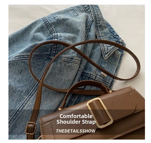Detail of dark brown leather crossbody bag with gold buckle and adjustable strap