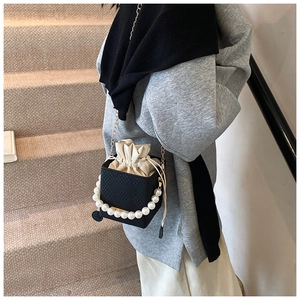 Detail of black box bucket bag with pearl handle and cream drawstring inner bag
