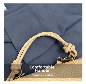 Close-up of beige woven leather handbag handle with a stylish knot and gold metal hook