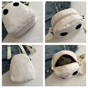Vue détaillée d'un sac bandoulière blanc en velours côtelé avec un visage de dessin animé