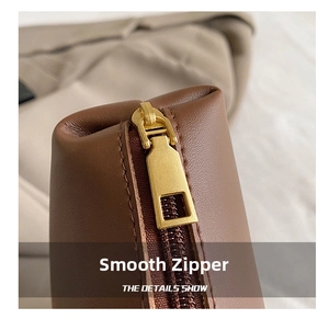 Close-up of golden rectangular metal zipper on brown pebble leather bucket bag detail