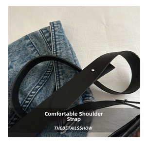 Detail of smooth black leather strap with silver rivets on a denim fabric background