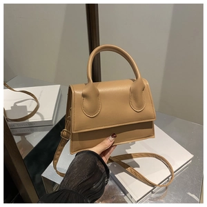 Detail of camel brown crossbody bag showing top handle, leather texture and adjustable strap