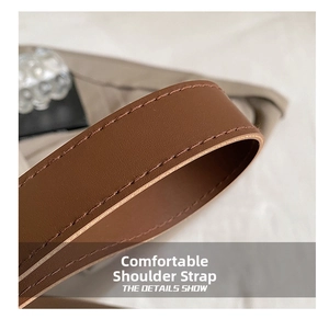 Close-up of brown leather shoulder strap with reinforced stitching on a bucket bag
