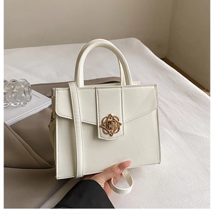 Détail d'un sac à main en cuir blanc avec fermoir floral en métal doré et texture