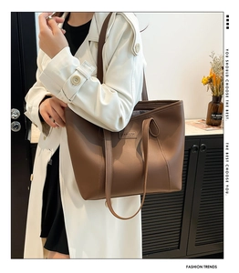 Détail d'un grand sac cabas en cuir marron avec étiquette FASHION sur trench blanc