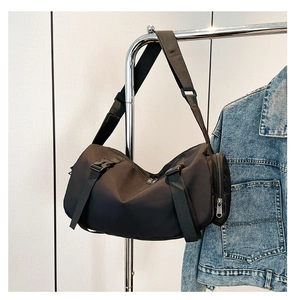 Close-up of black Oxford crossbody bag with plastic buckle hanging on metal hanger