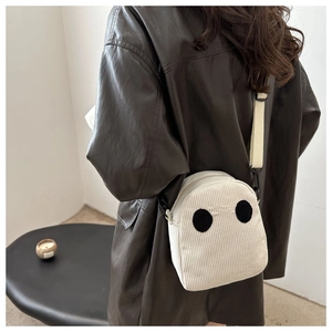 Détail du sac bandoulière en velours côtelé blanc avec patchs yeux noirs et sangle
