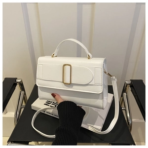 Close-up of white leather handbag with golden rectangular buckle and textured finish