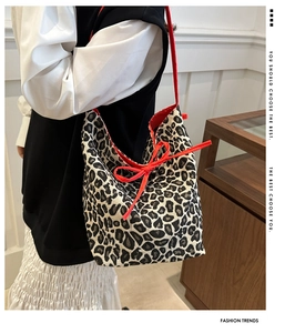 Detailed leopard print tote bag with red bow accent and vibrant red lining on shoulder