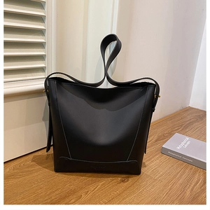 Detail of minimalist black leather bucket bag with matte finish and subtle embossed logo