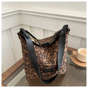 Detail of leopard print canvas bucket bag with black leather strap and silver buckle