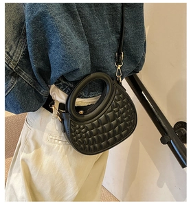 Detail of black quilted PU leather handbag with circular handle and gold hardware