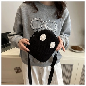 Détail du sac en velours côtelé noir avec patchs ronds blancs et bandoulière en tissu