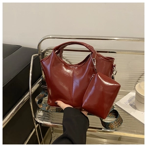 Detail of dark red glossy leather tote bag featuring ethnic style embroidered strap