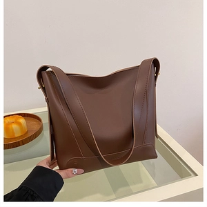 Detail of the brown leather bucket bag with Fashion & Bag embossed logo and wide strap