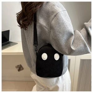 Détail du sac bandoulière noir en velours côtelé avec de jolis patchs en forme d'yeux