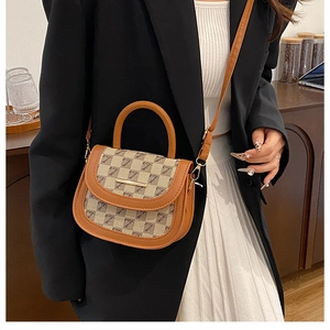 Detailed close-up of checkered saddle bag with gold hardware and brown leather accents