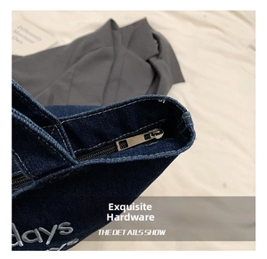 Detail of dark blue denim tote with metal zipper and white days letter embroidery