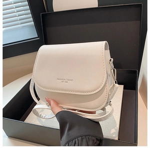 Detail of white PU leather saddle bag featuring gold-stamped fashion logo and flap design