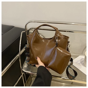 Brown patent leather tote bag set with patterned wide strap in detailed indoor view