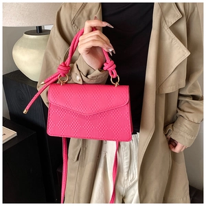 Macro detail of rose pink quilted handbag featuring elegant knotted handle and gold hardware