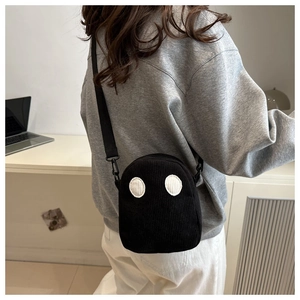 Détail du sac à bandoulière en velours côtelé noir avec yeux de dessin animé sur modèle