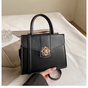 Détail d'un sac à main vintage en cuir noir avec un élégant fermoir doré en fleur