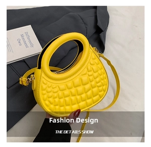 Detail view of yellow half-moon handbag with textured geometric quilted pattern