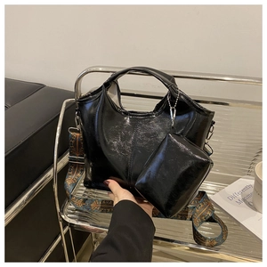 Detail of black glossy leather tote bag with a colorful bohemian embroidered wide strap