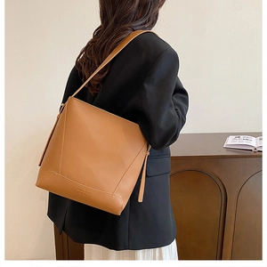 Detailed view of caramel leather tote bag showing side straps and Fashion & Bag engraving