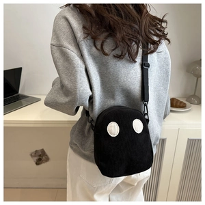 Détail du sac à bandoulière en velours côtelé noir avec un design d'yeux de dessin animé