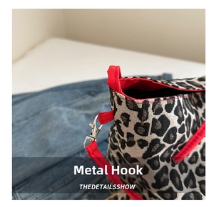 Macro detail of silver metal hook on leopard print bucket bag with red trim