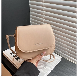 Close-up of beige saddle bag showing smooth leather texture and embossed logo