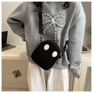 Détail du petit sac bandoulière en velours noir avec motif fantôme sur un sweat gris
