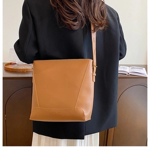 Close-up of brown leather bucket bag with gold hardware and embossed branding logo