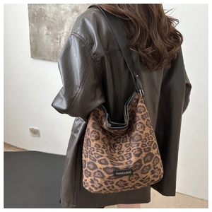 Close-up of leopard print suede tote bag with black strap and fashion label on shoulder