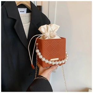 Detail of orange woven bucket bag featuring large pearl handle and drawstring closure