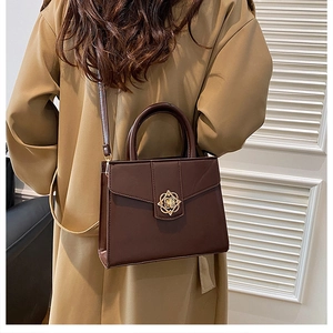 Détail du sac à main en cuir marron foncé avec fermoir floral doré sur un mannequin