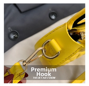 Detail of yellow quilted leather bag showing gold hardware and detachable strap clasp