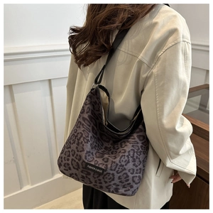 Detail shot of leopard print tote bag with black strap and fashion label on model